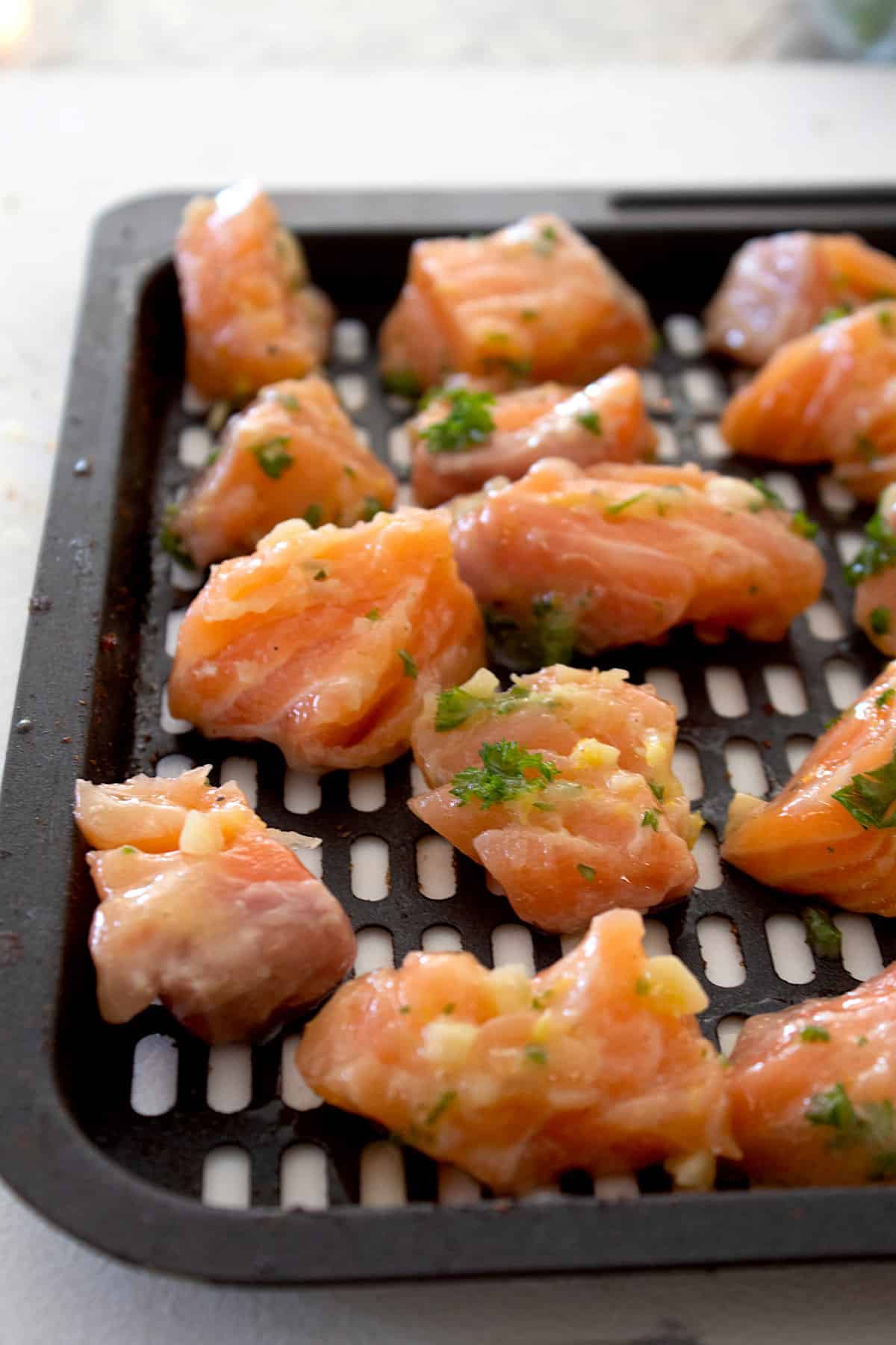 raw salmon bites on an air fryer baking sheet