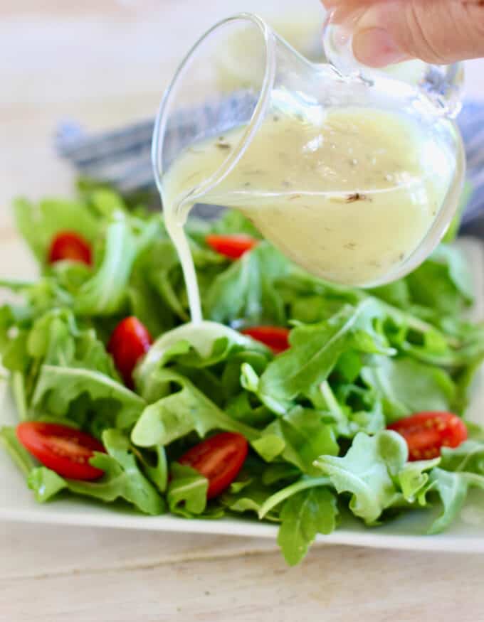 pouring greek dressing on salad