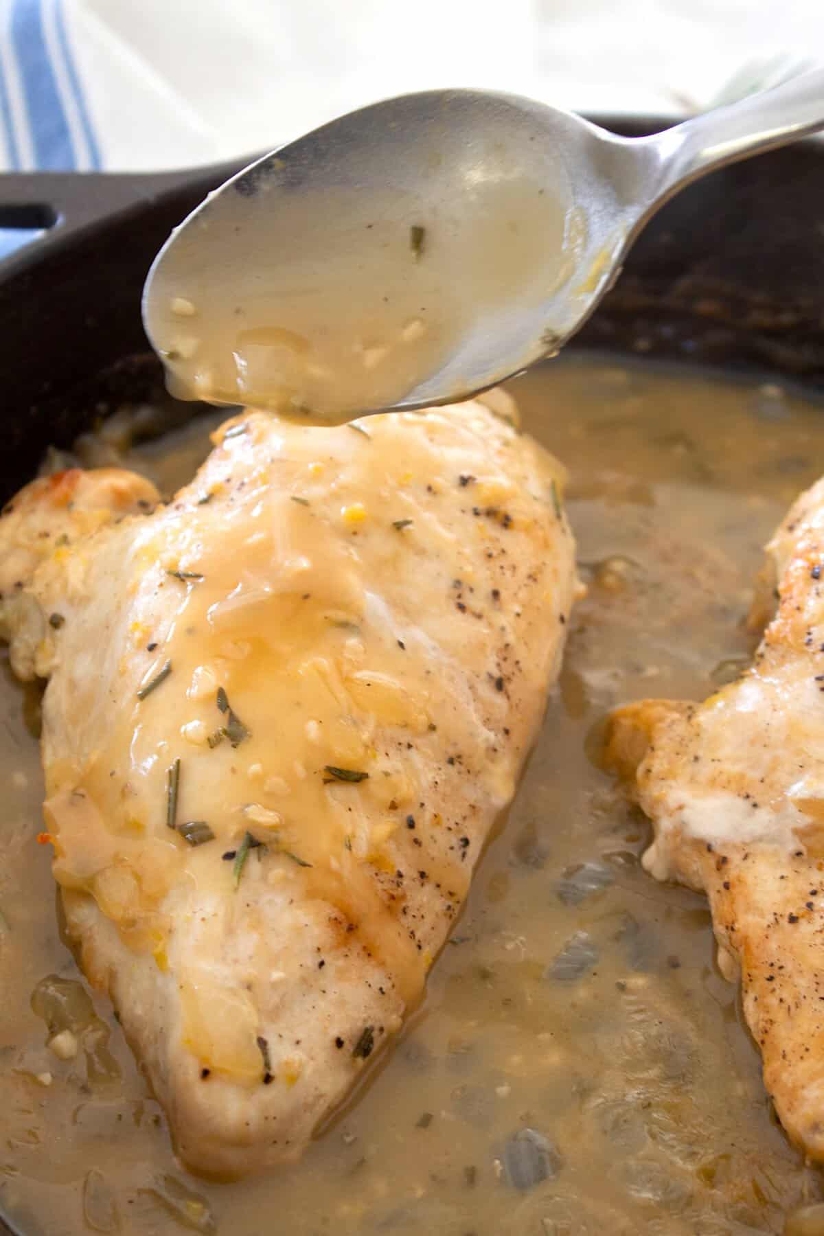 spooning pan sauce onto chicken