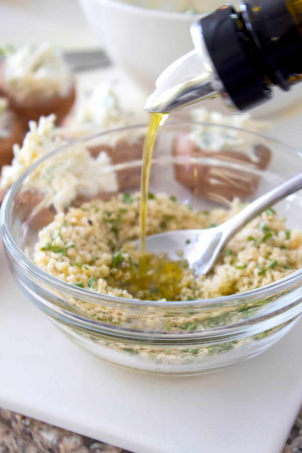 panko crumb topping in a clear bowl adding olive oil 