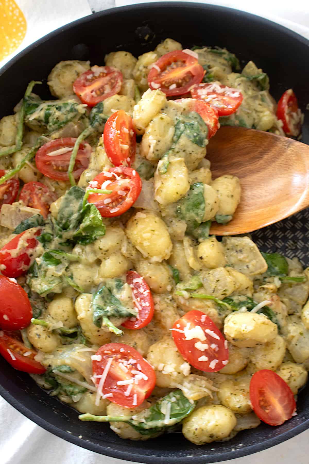 overhead view of gnocchi pesto skillet with a wooden spoon