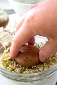 pressing cream cheese stuffed mushroom into panko crumb mixture