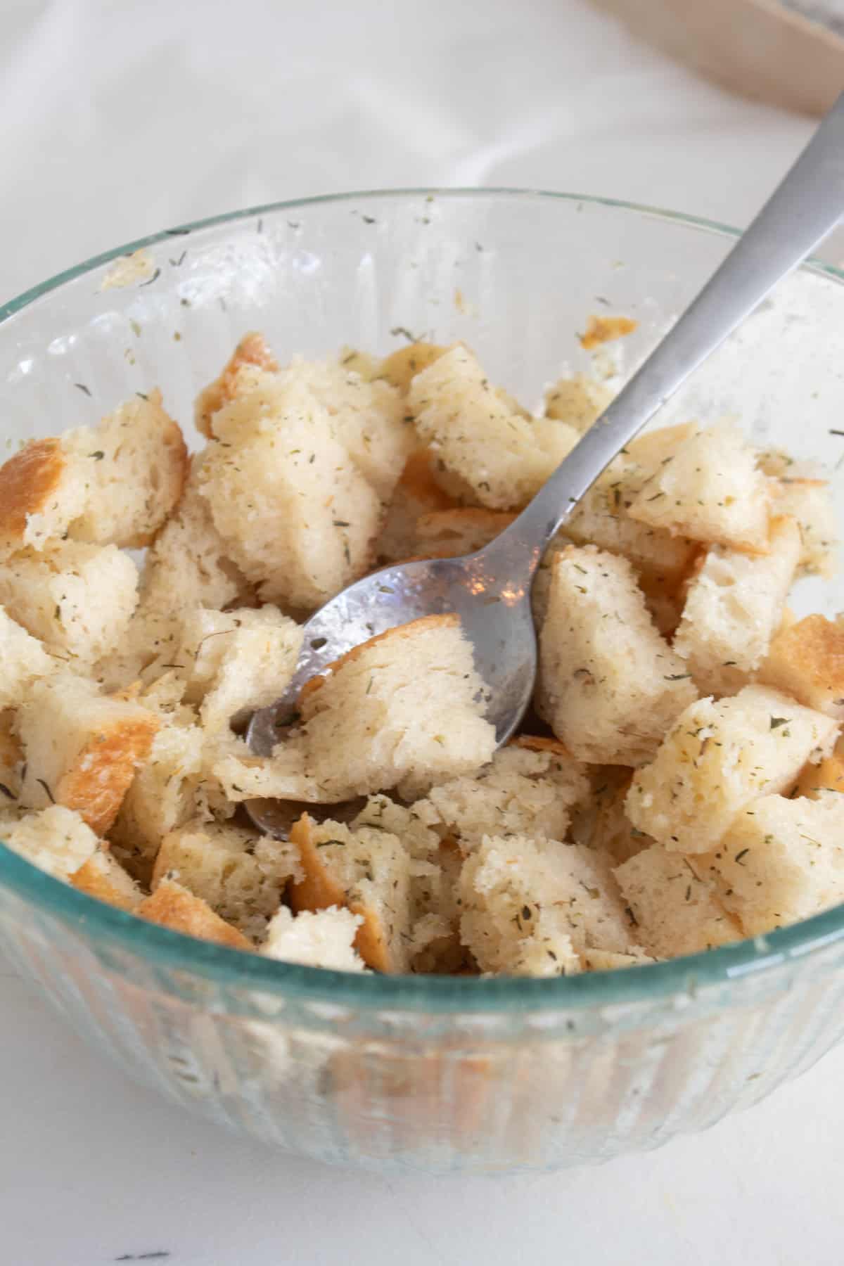 tossing bread cubes in butter in a bowl