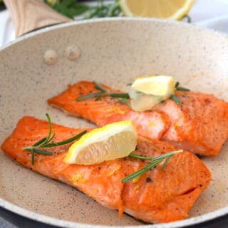 cream colored pan with salmon cooked in it and lemon for garnish
