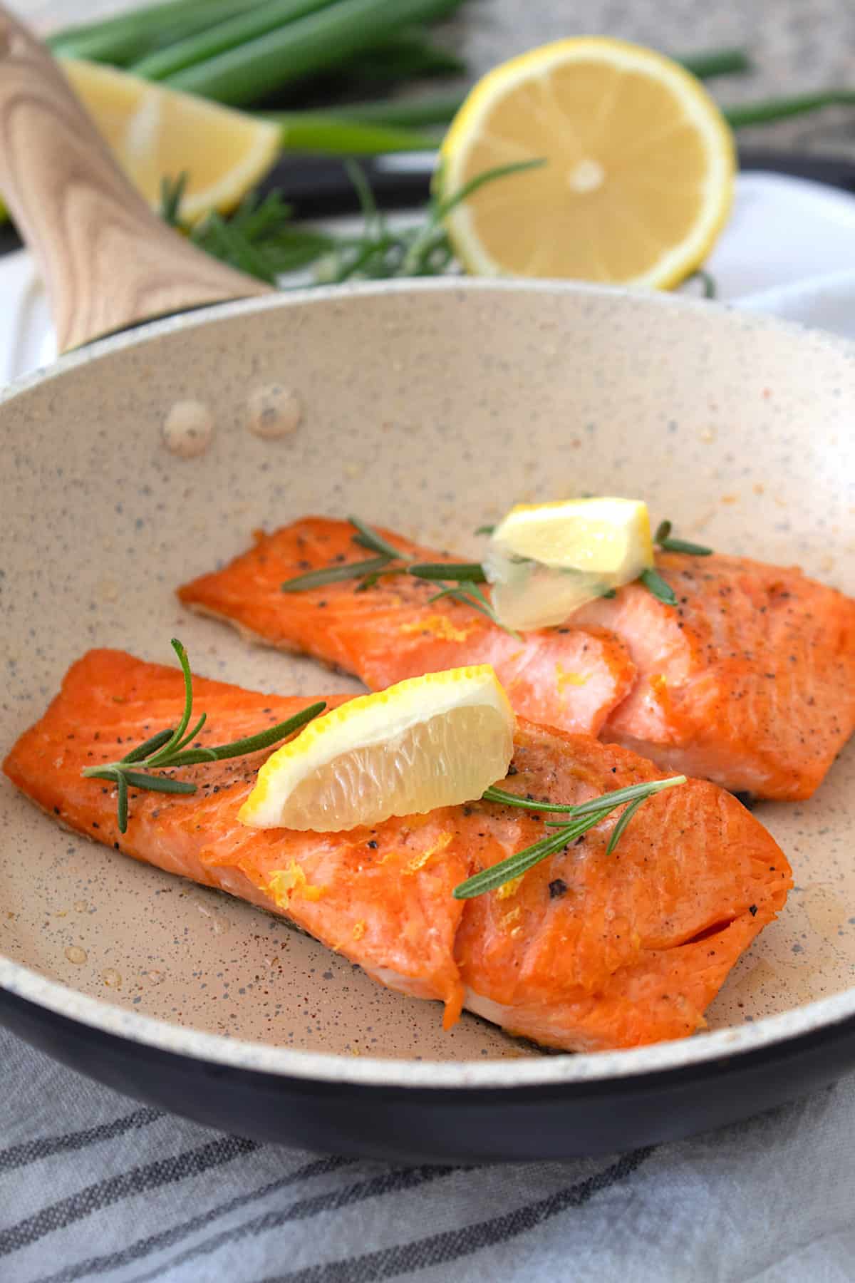 cream colored pan with salmon cooked in it and lemon for garnish