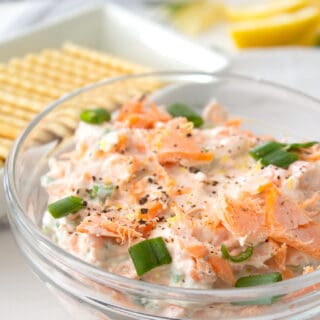 smoked salmon dip in a clear bowl with green onion garnish