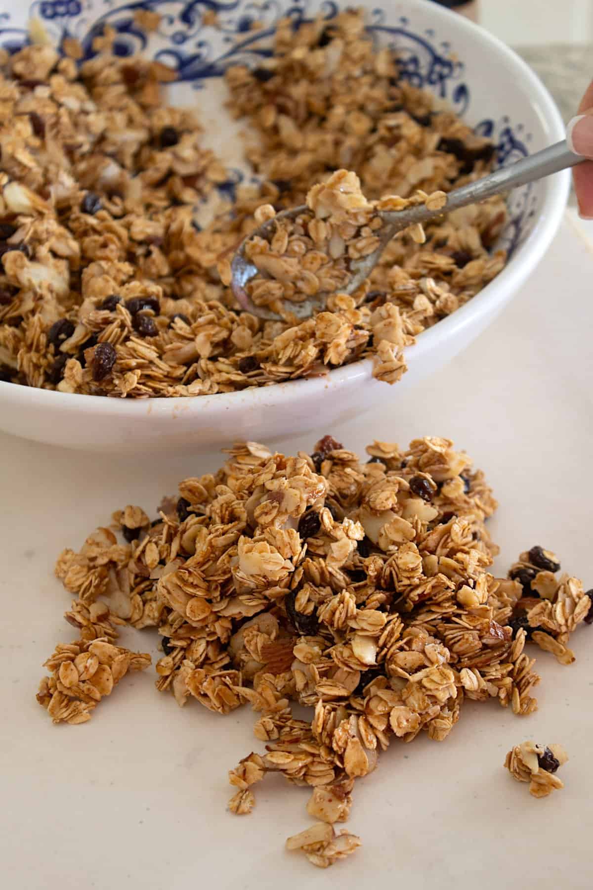 spreading granola on parchment paper before baking