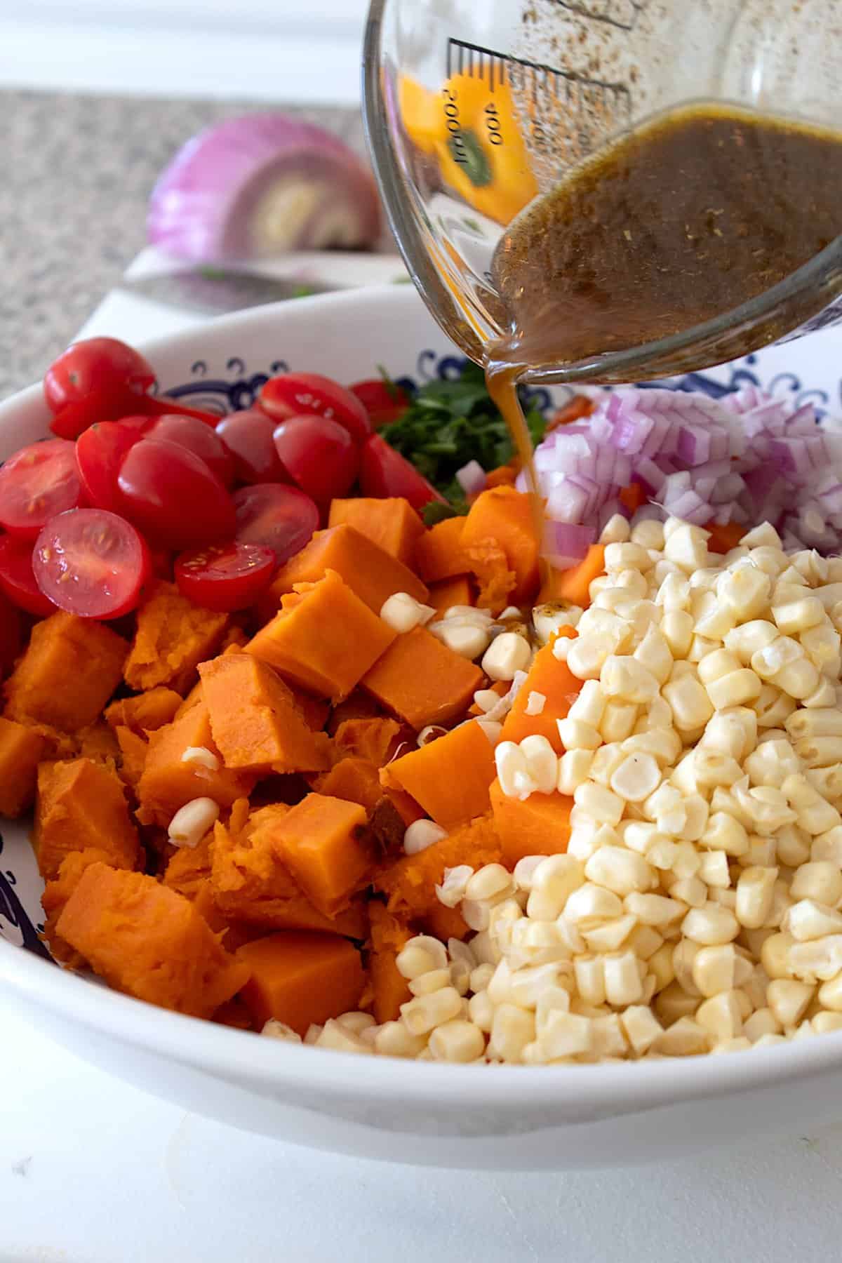 drizzling dressing over sweet potato salad
