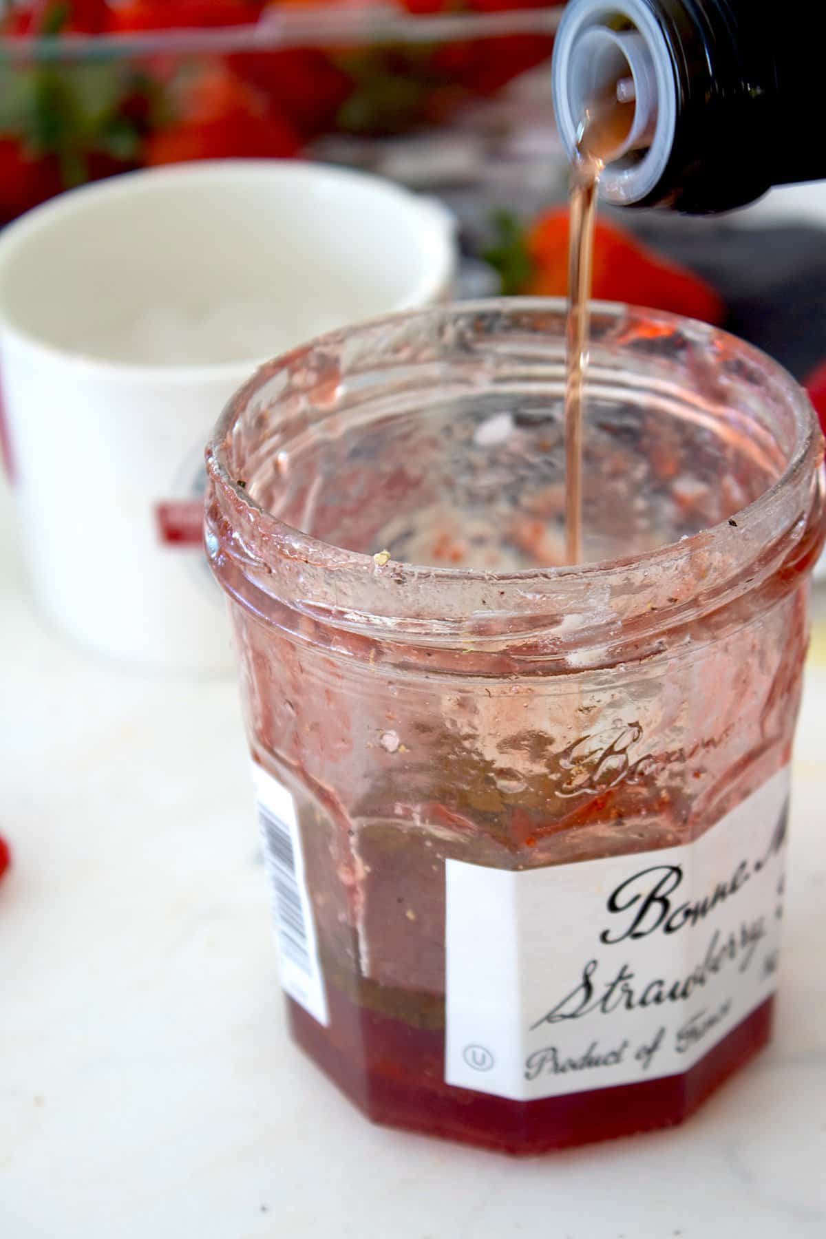 pouring red wine vinegar into a jam jar