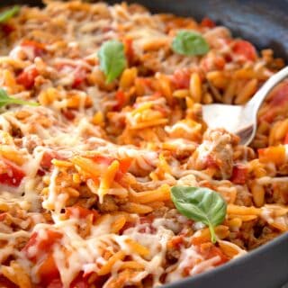 view of tomato orzo ground turkey skillet in a pan with a fork in it