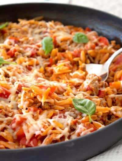 view of tomato orzo ground turkey skillet in a pan with a fork in it