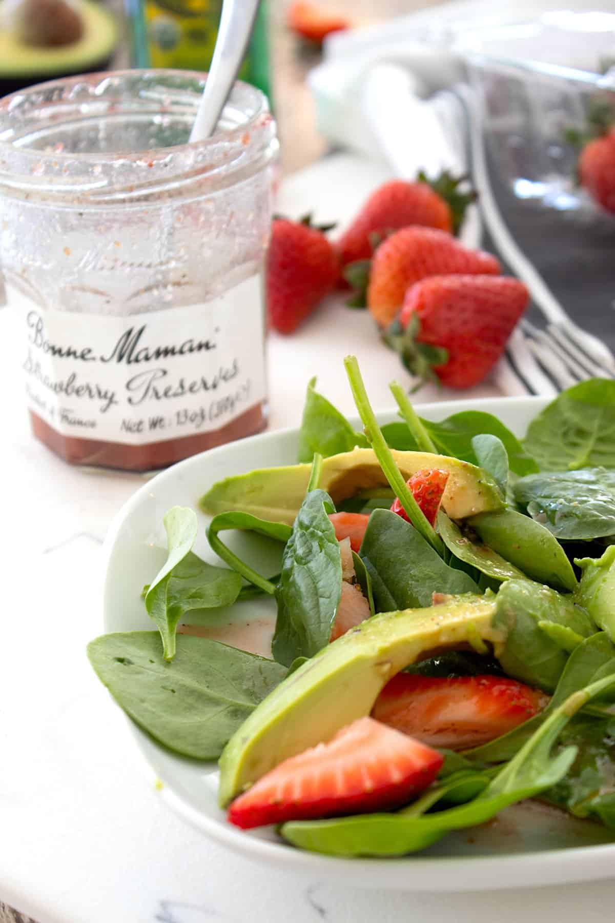 spinach salad with strawberry dressing in jam jar in background