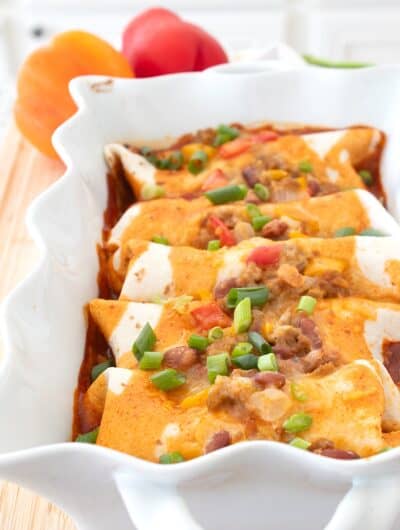 ground turkey enchiladas in a white casserole dish with red sauce