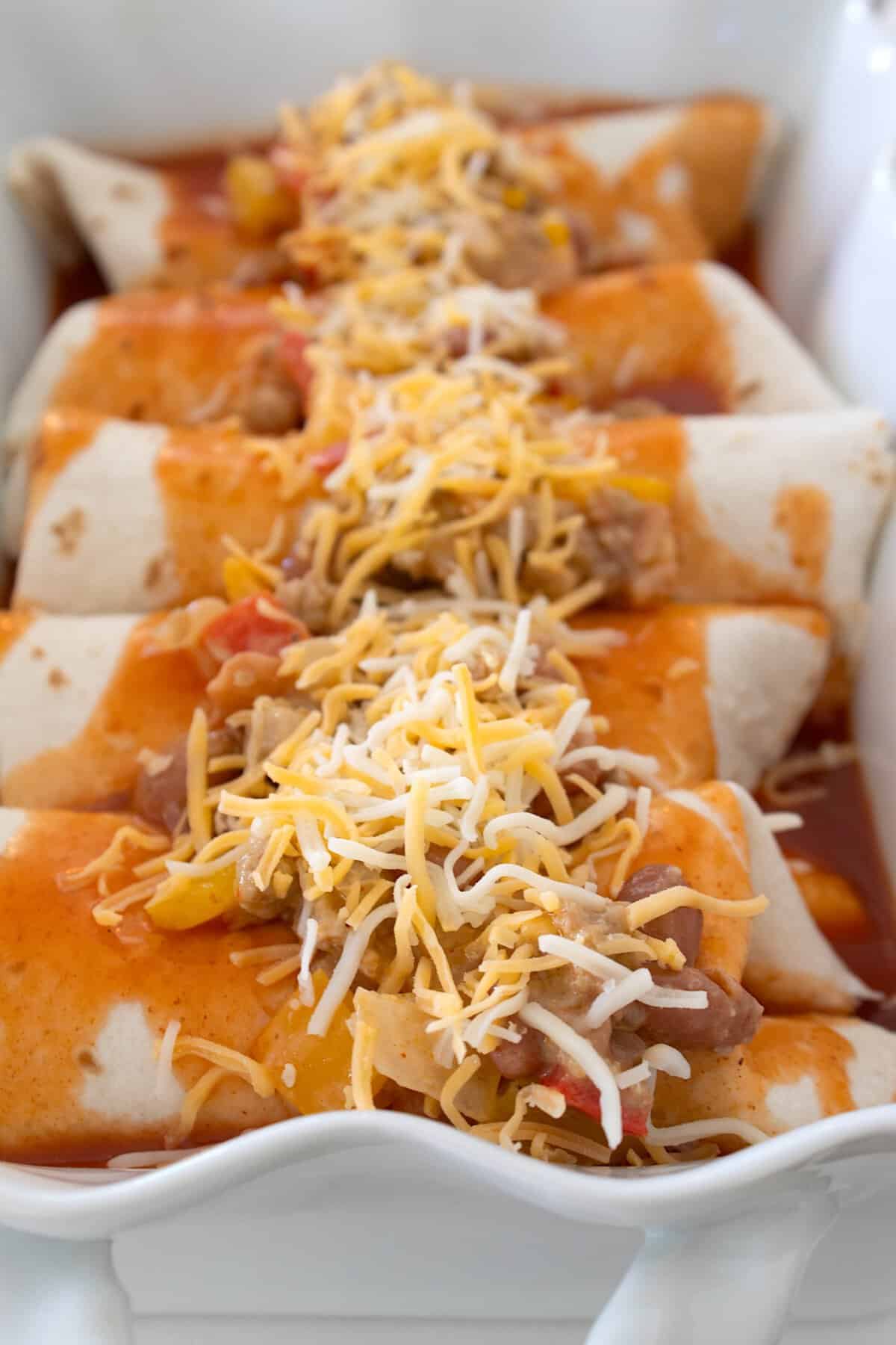 rolled up ground turkey enchiladas before baking in a white casserole dish