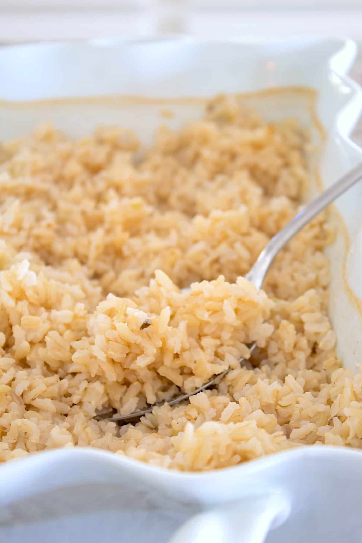 spoonful of fluffy brown rice in a white casserole dish