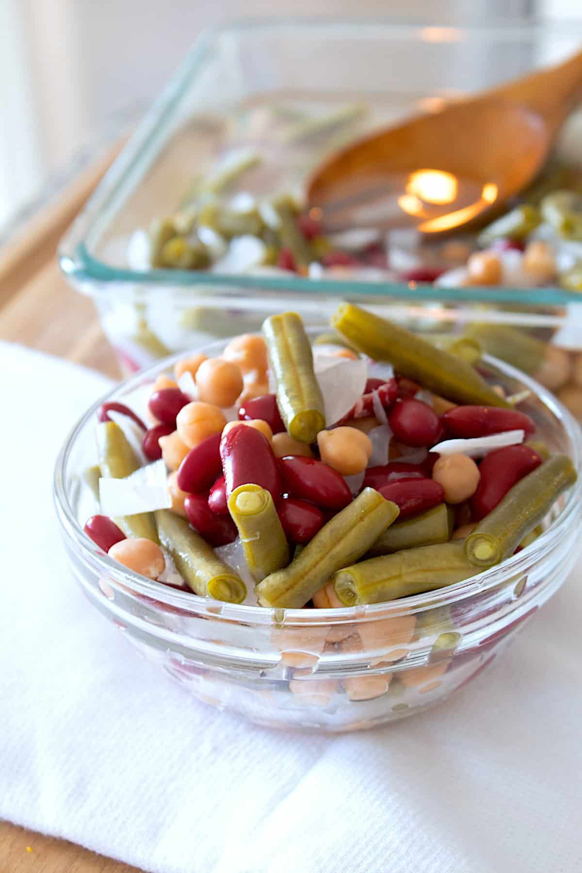 quick pickled three bean salad in a clear dish on a dish towel