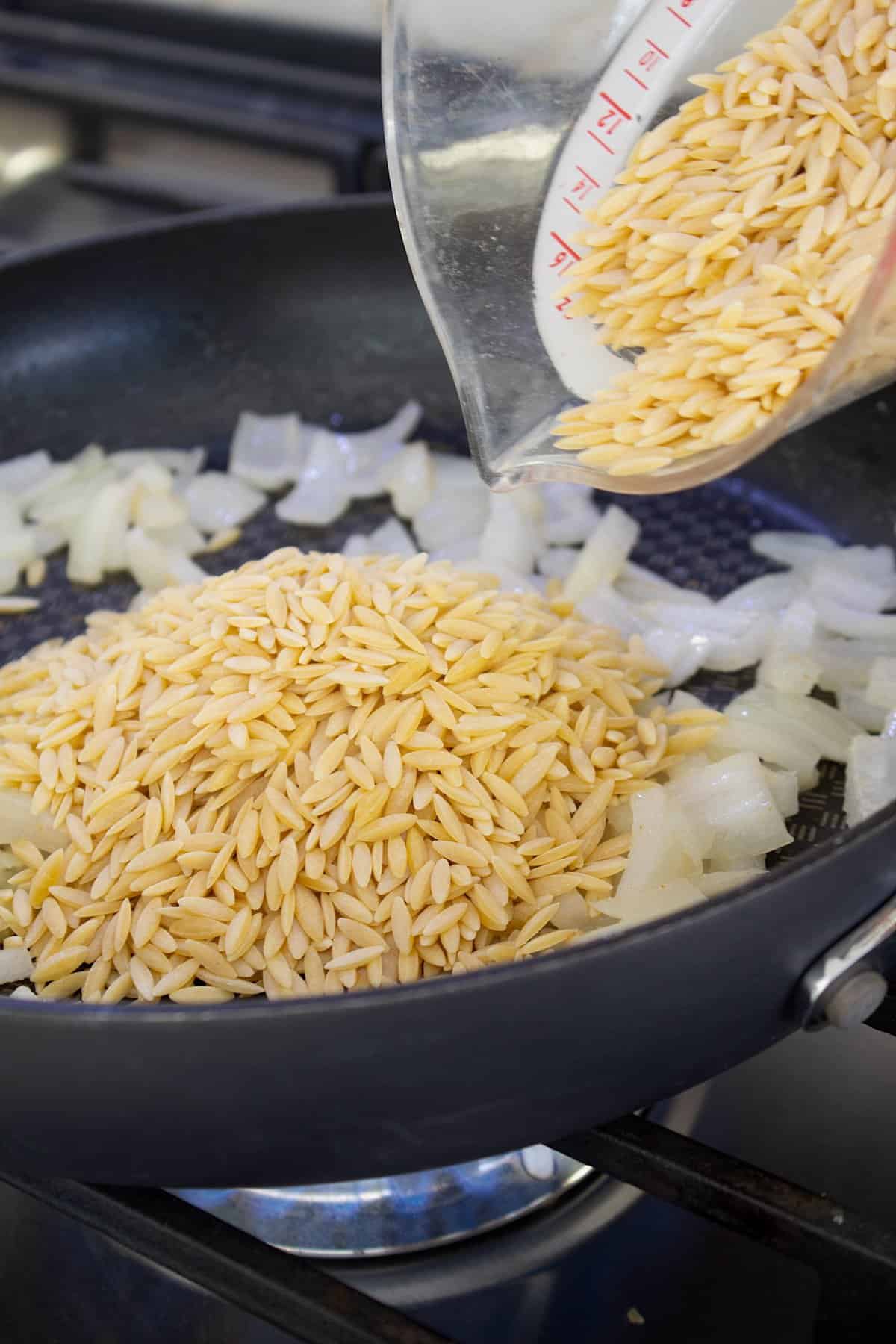 toasting orzo in pan with onions and olive oil