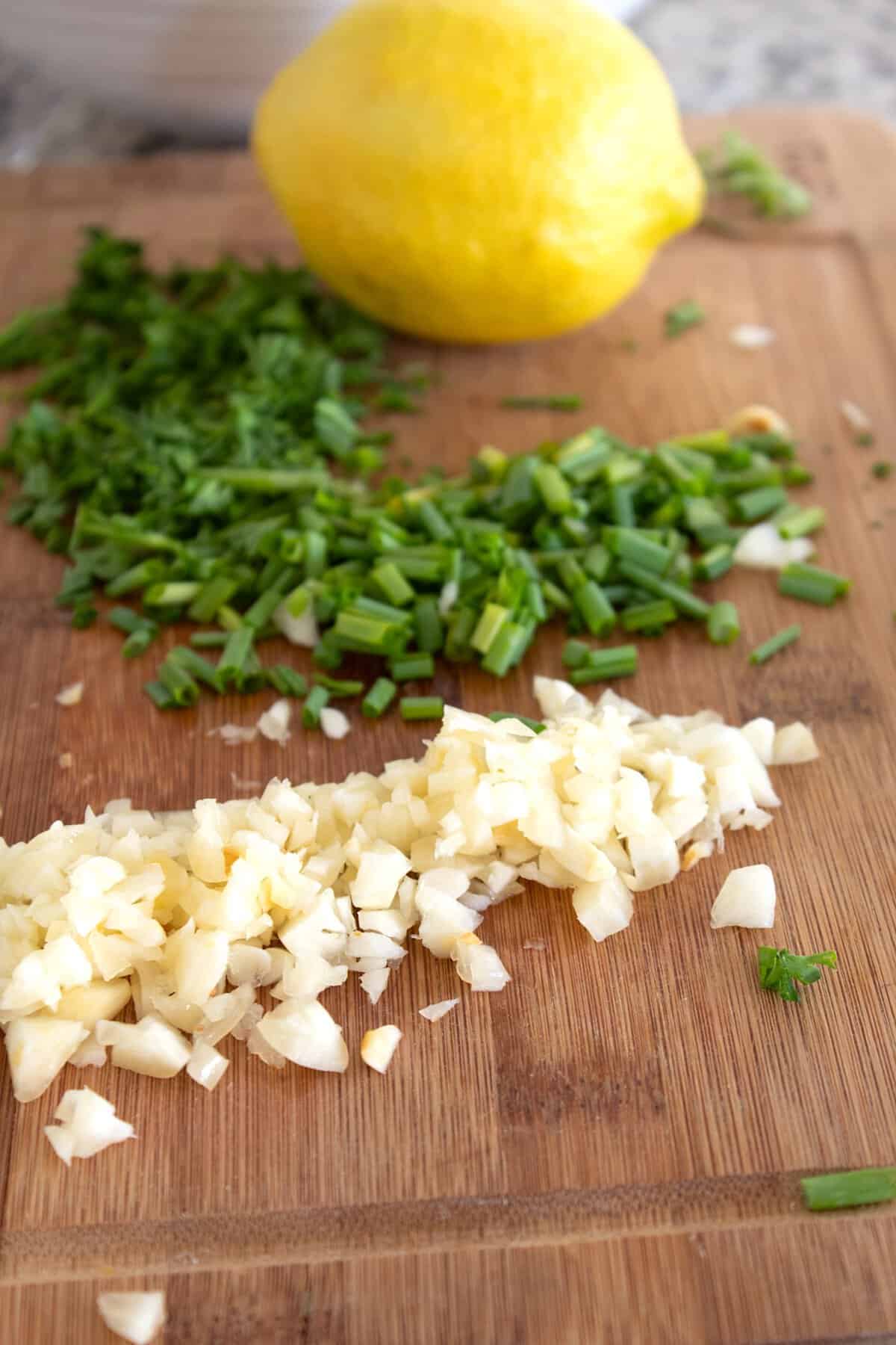 chopped garlic chives and parsley on a cutting board