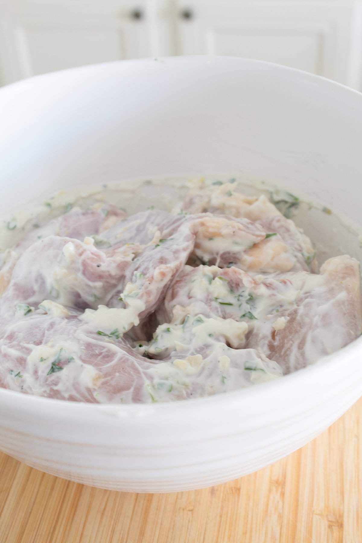 chicken marinating in a bowl in yogurt