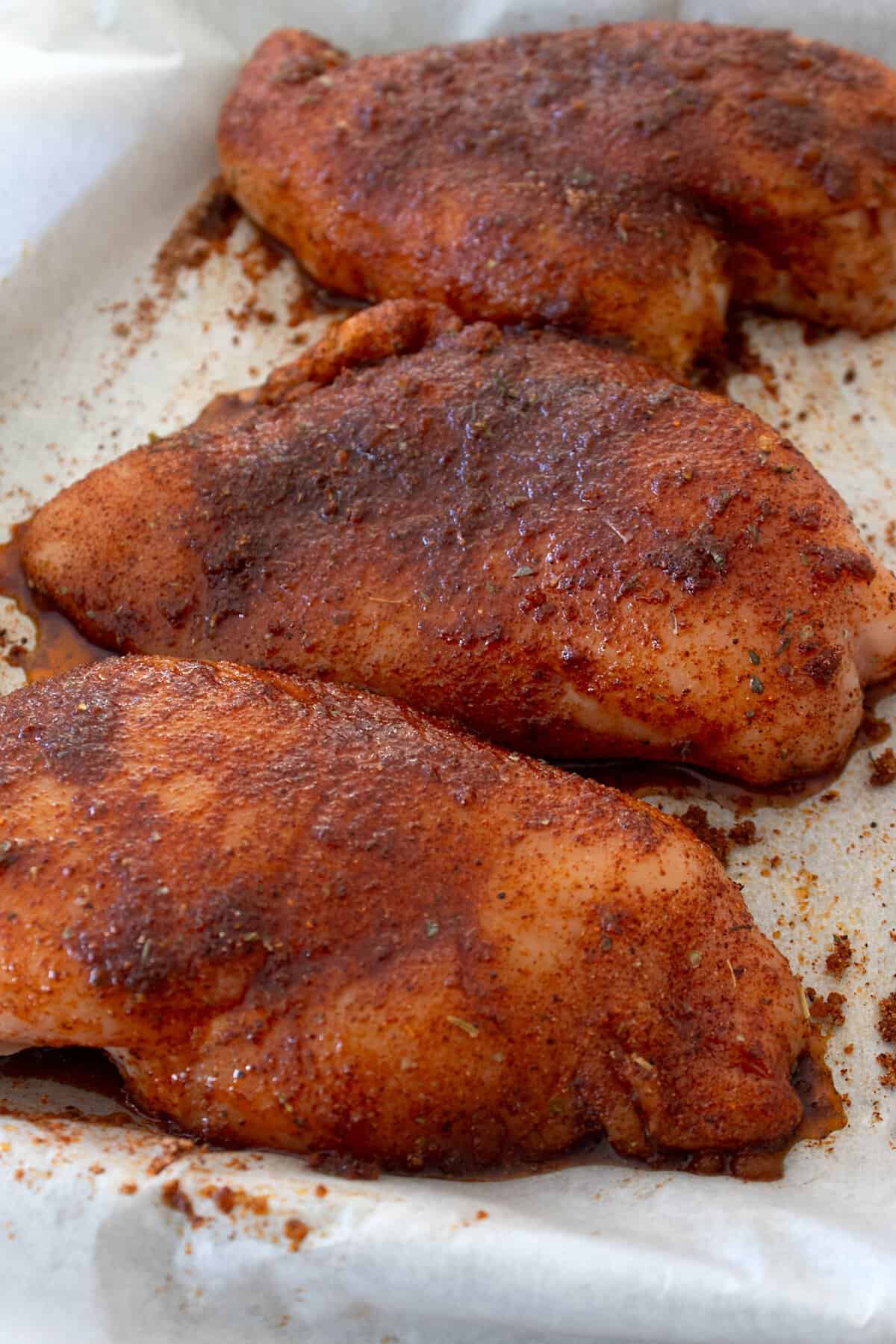 blackened chicken breasts on a sheet pan raw before baking