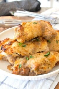 white plate with baked chicken thighs on it
