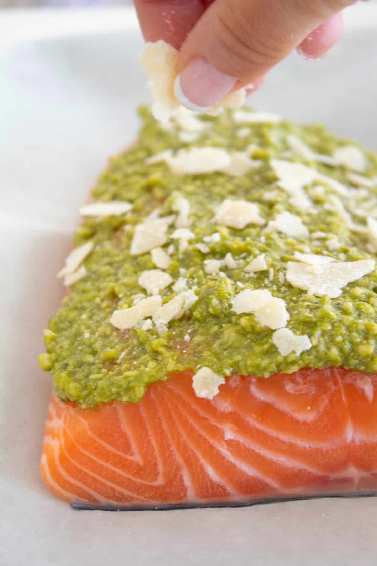 salmon with pesto and parmesan before baking on a sheet pan