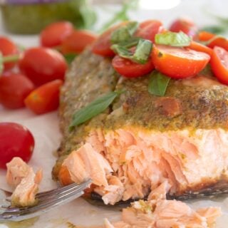 pesto salmon garnished with cherry tomatoes an fresh basil