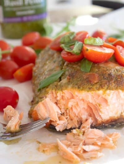 pesto salmon garnished with cherry tomatoes an fresh basil
