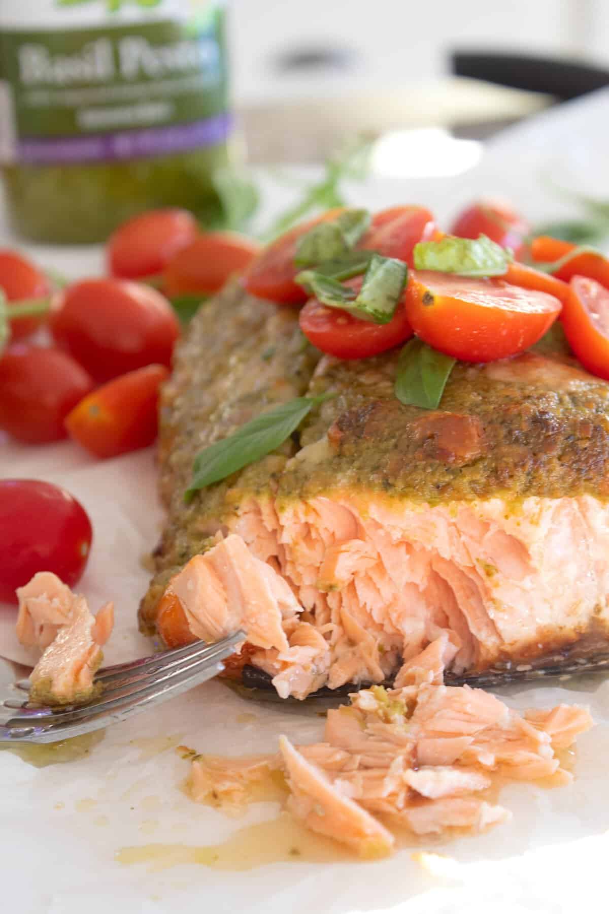 pesto salmon garnished with cherry tomatoes an fresh basil