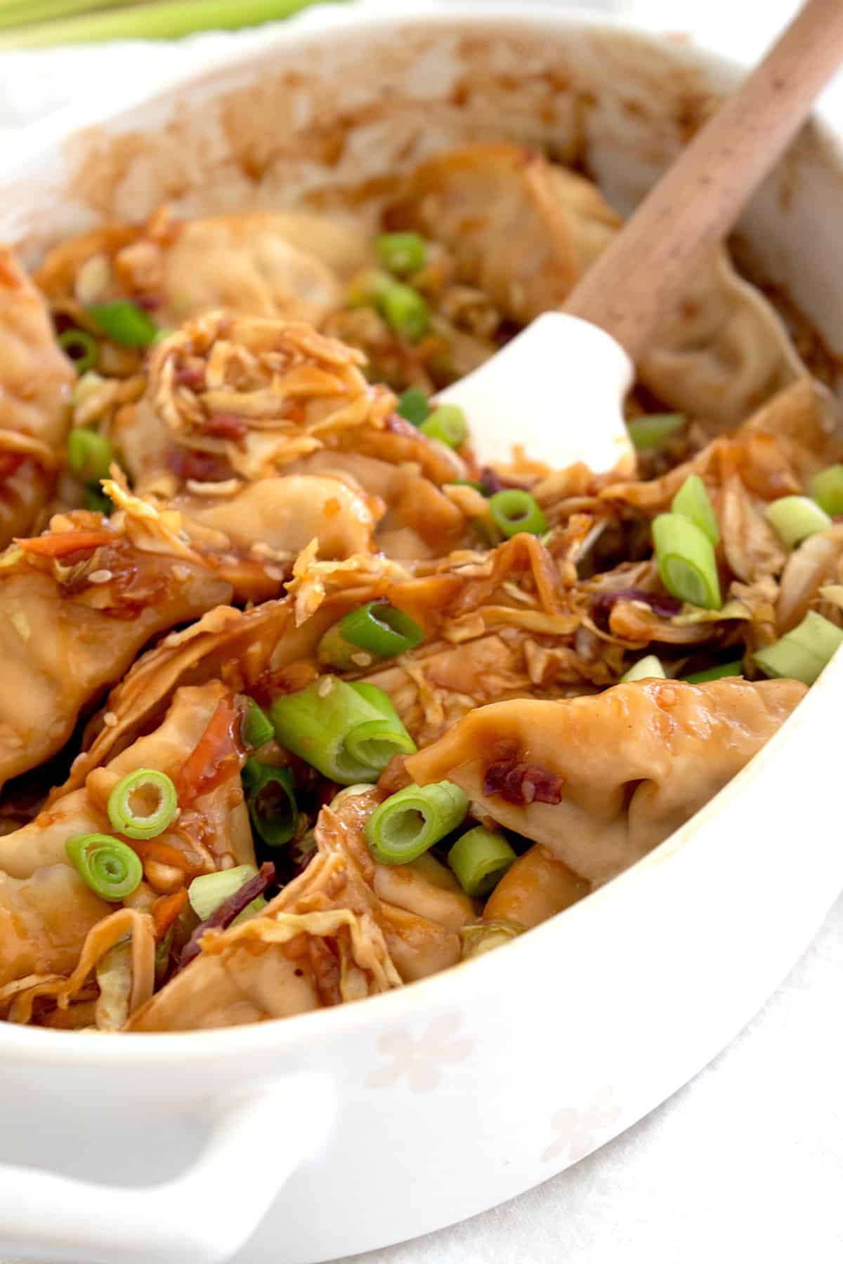 overhead view of stirring wontons baked in a casserole dish