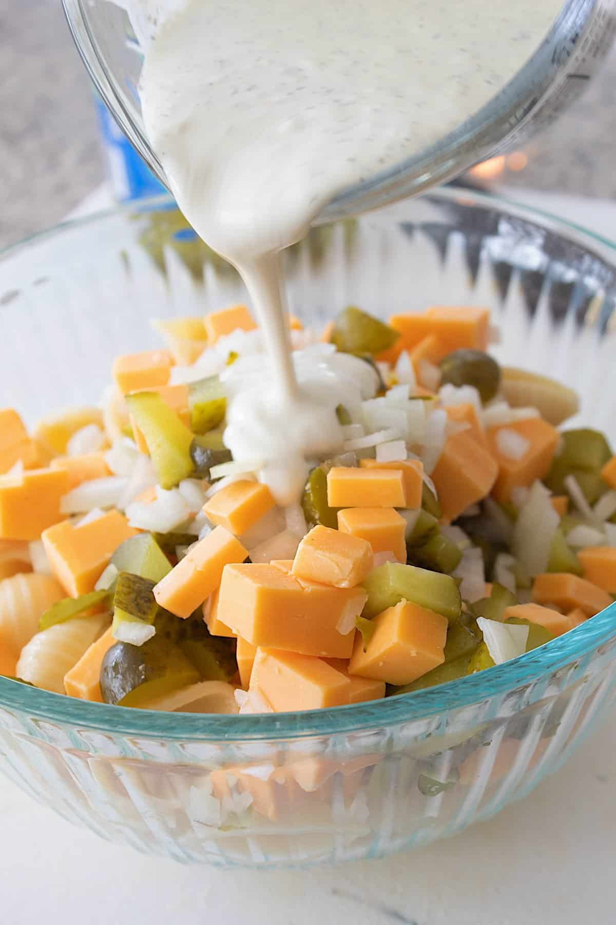 pickle salad ingredients in a bowl with pickle dressing being poured on top