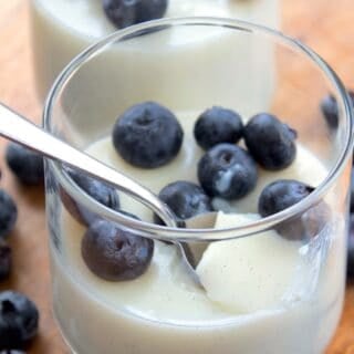 clear glass with vanilla pudding garnished with blueberries