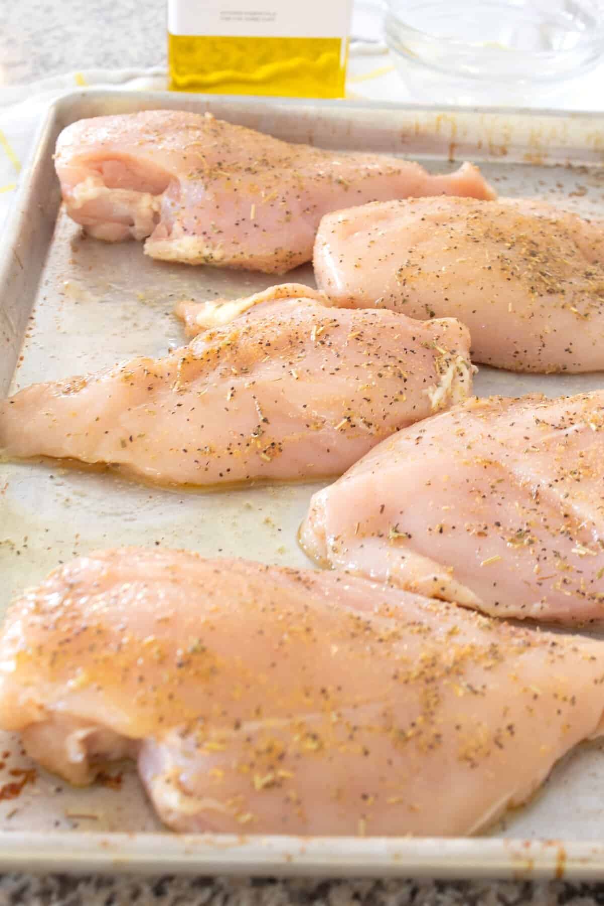 seasoned chicken breasts on sheet pan before baking