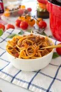 spaghetti in a bowl with tomatoes in the background