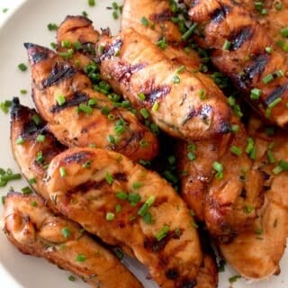overhead shot of grilled chicken tenders on a white plate