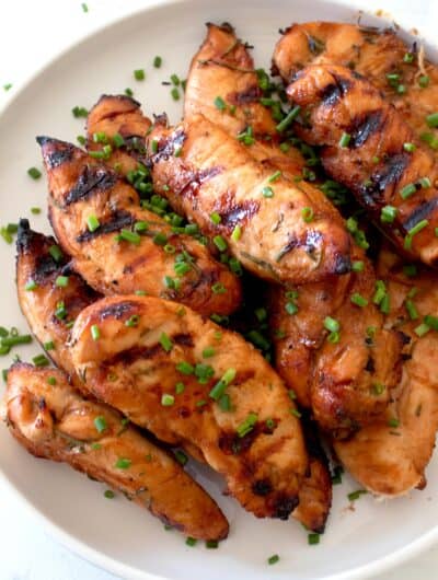 overhead shot of grilled chicken tenders on a white plate