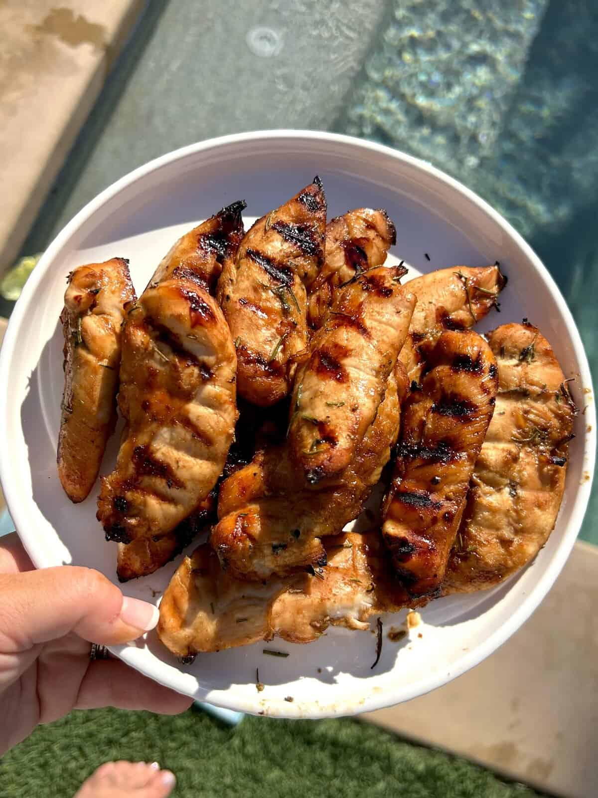 holding a plate of chicken tenders over a pool