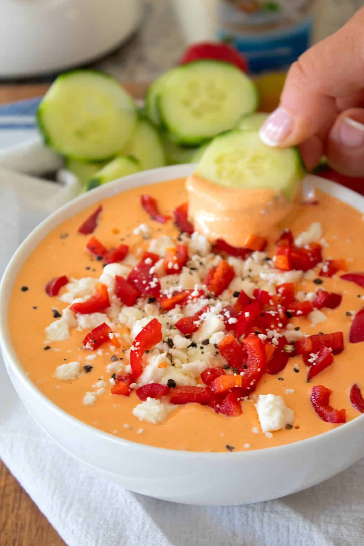 dipping a cucumber in red pepper dip