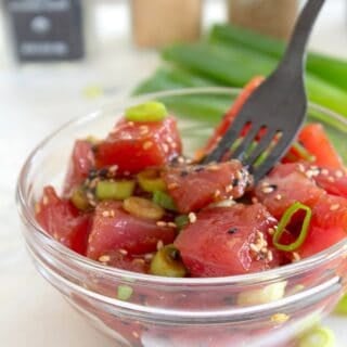 ahi poke in a clear bowl with a black fork