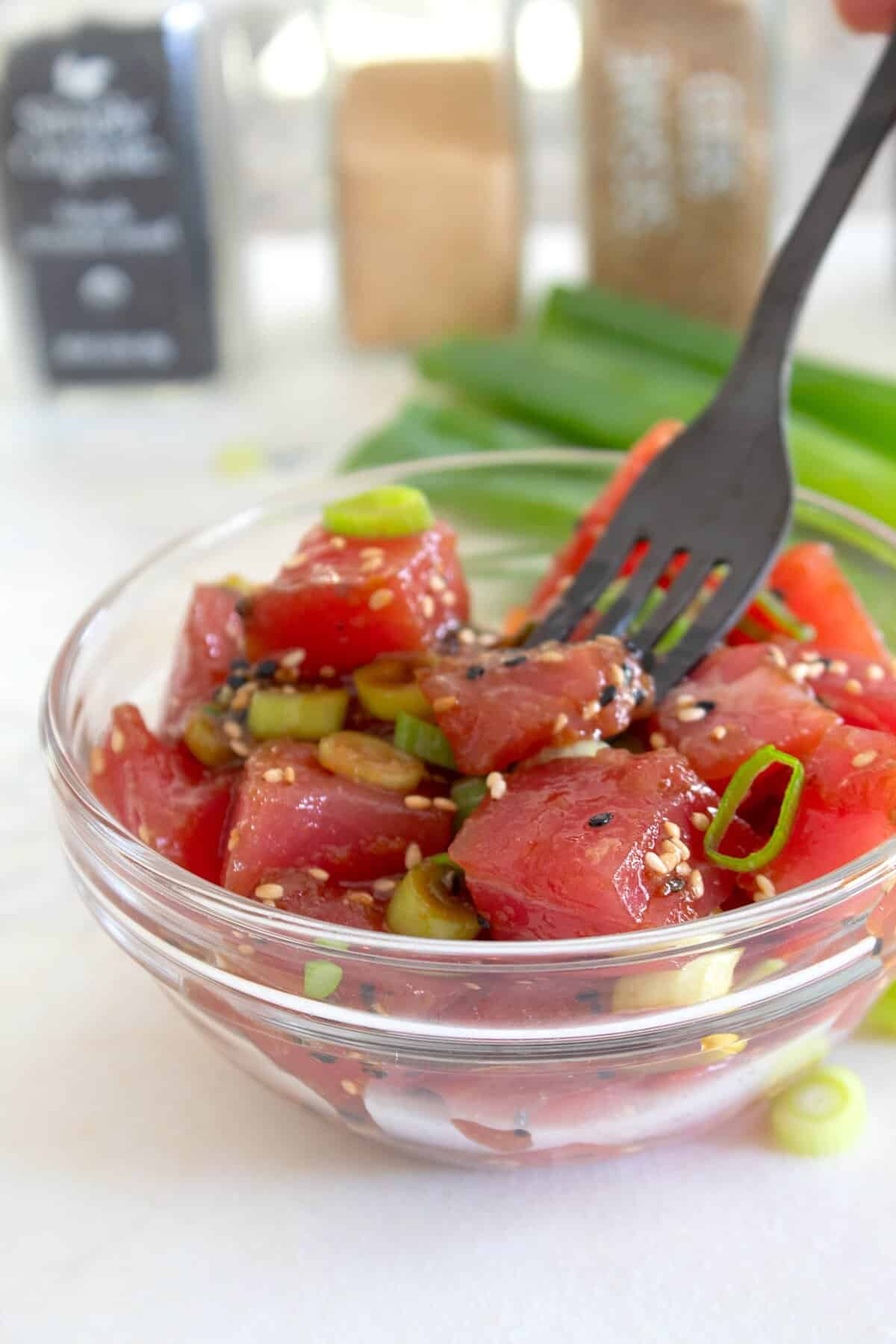ahi poke in a clear bowl with a black fork