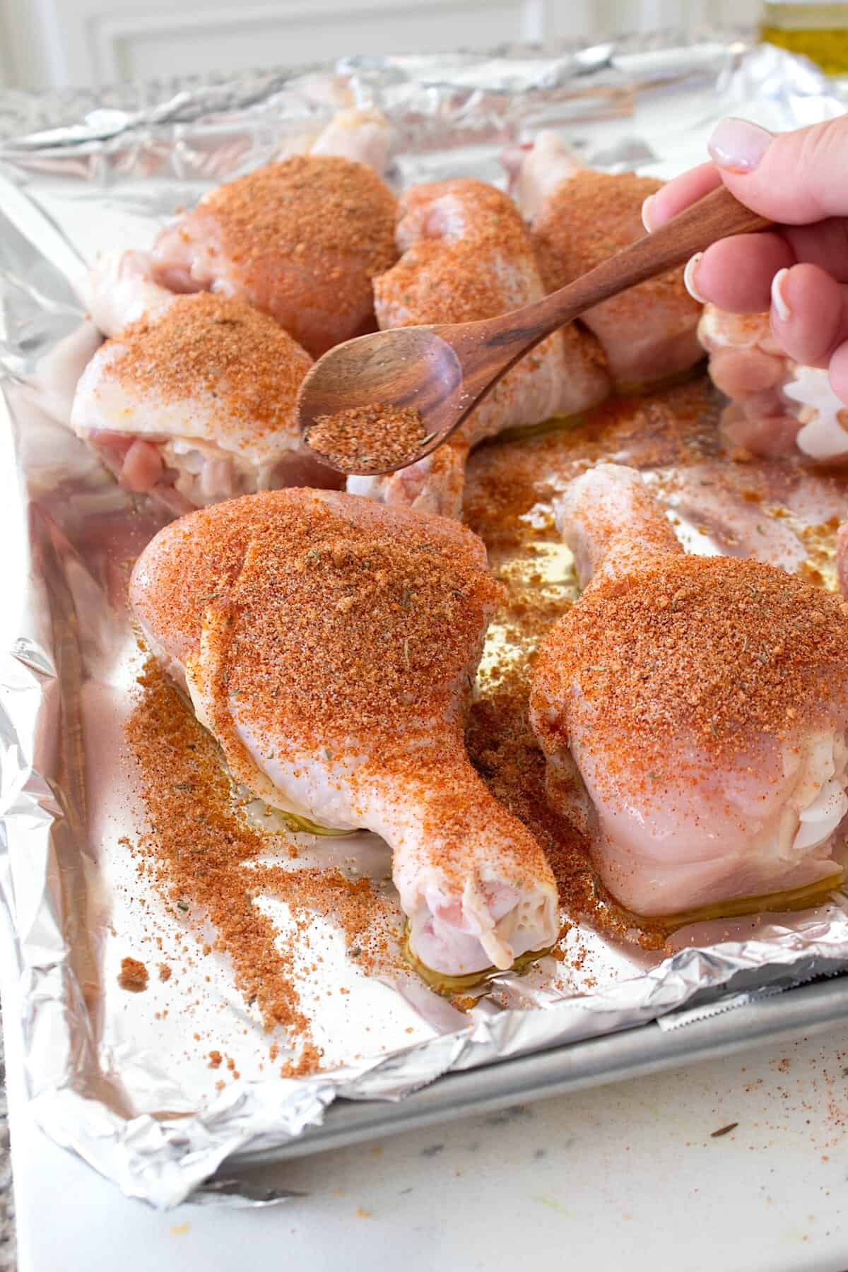 adding seasoning to chicken drumsticks