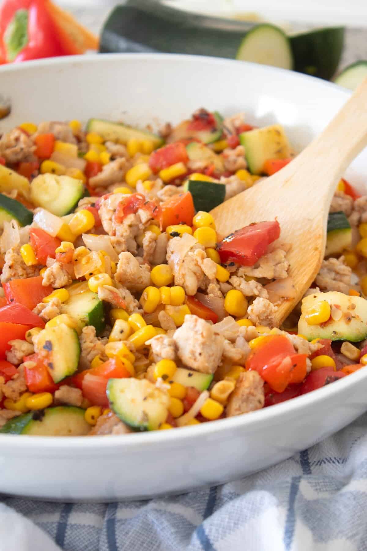 side view of chicken and zucchini skillet with spatula