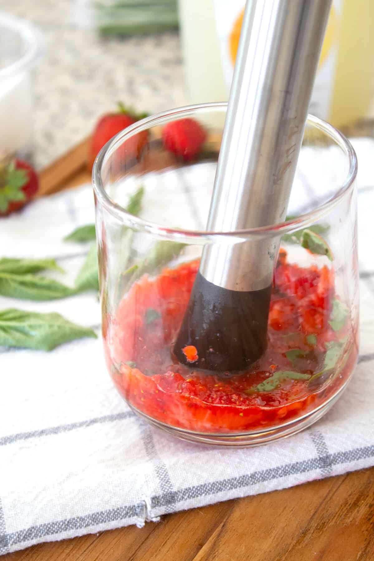 muddling strawberries and basil in a glass