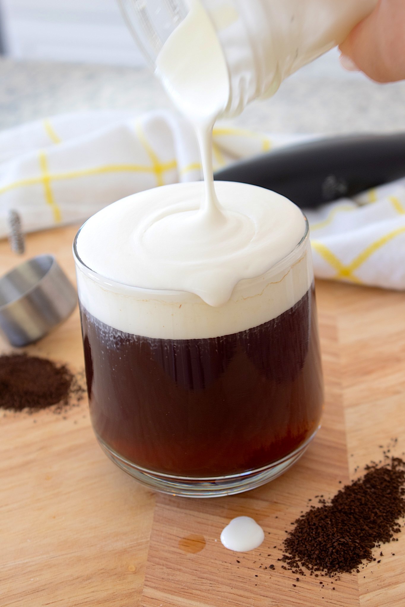 pouring cold foam over iced coffee