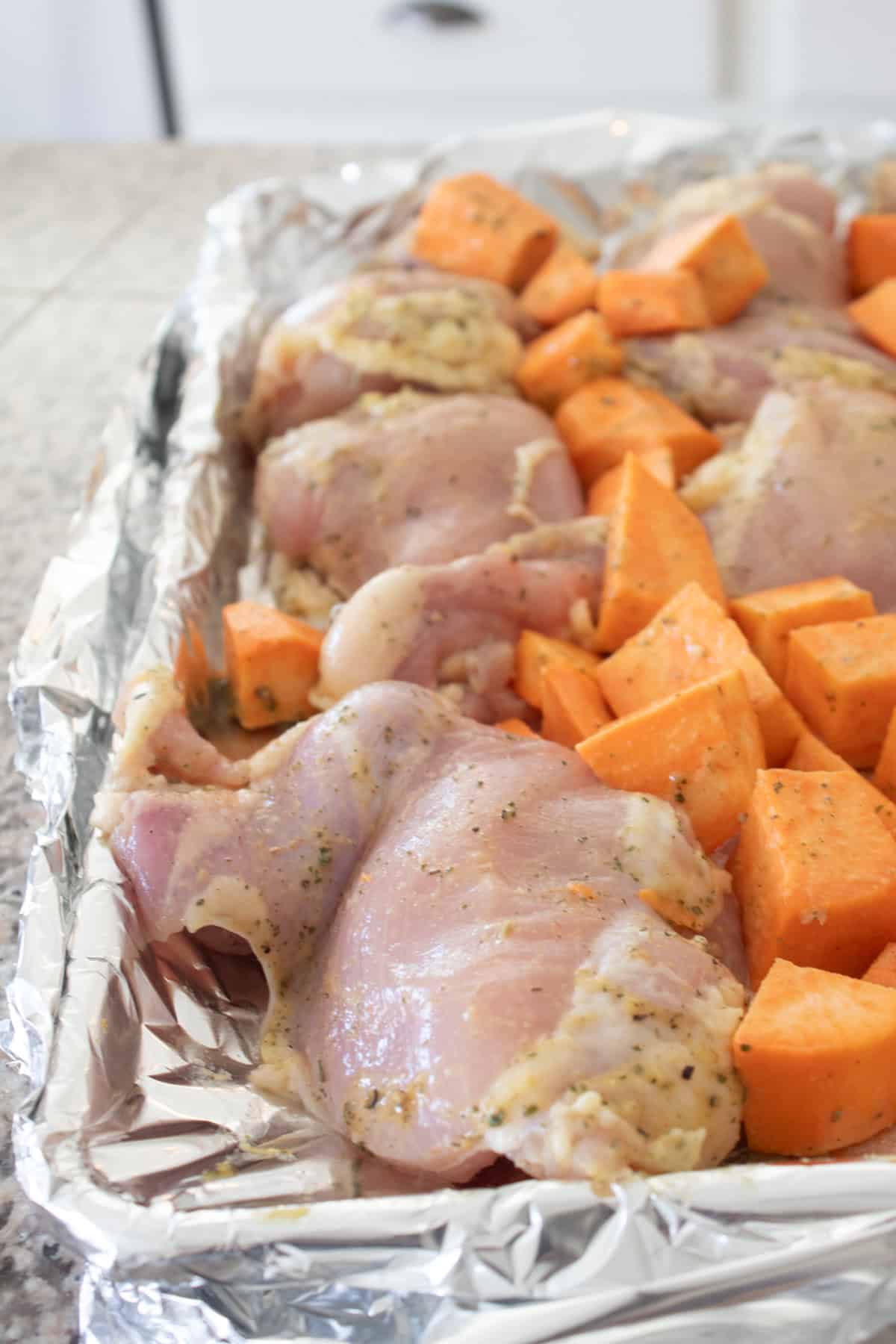 coated chicken and sweet potatoes on a sheet pan