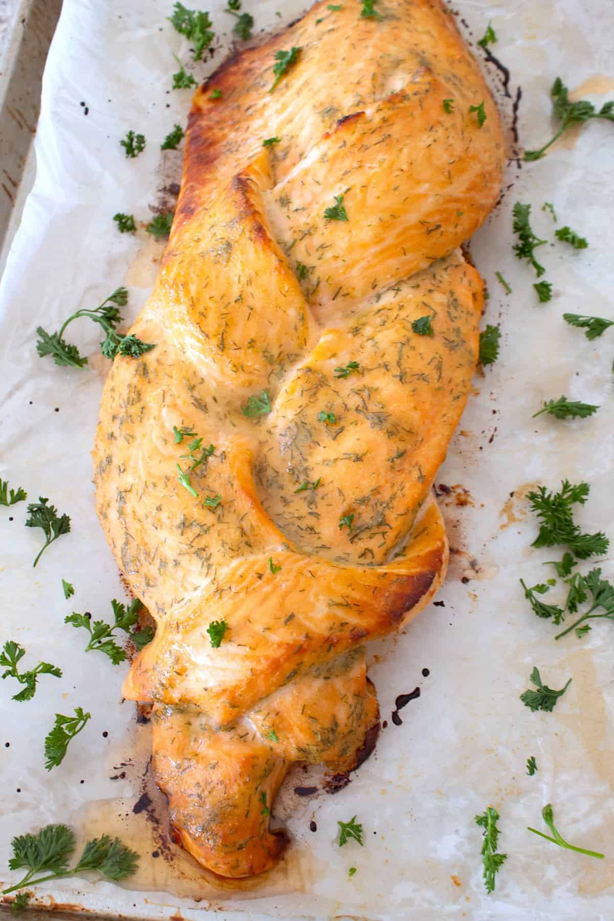 overhead view of braided salmon on sheet pan with parsley garnish