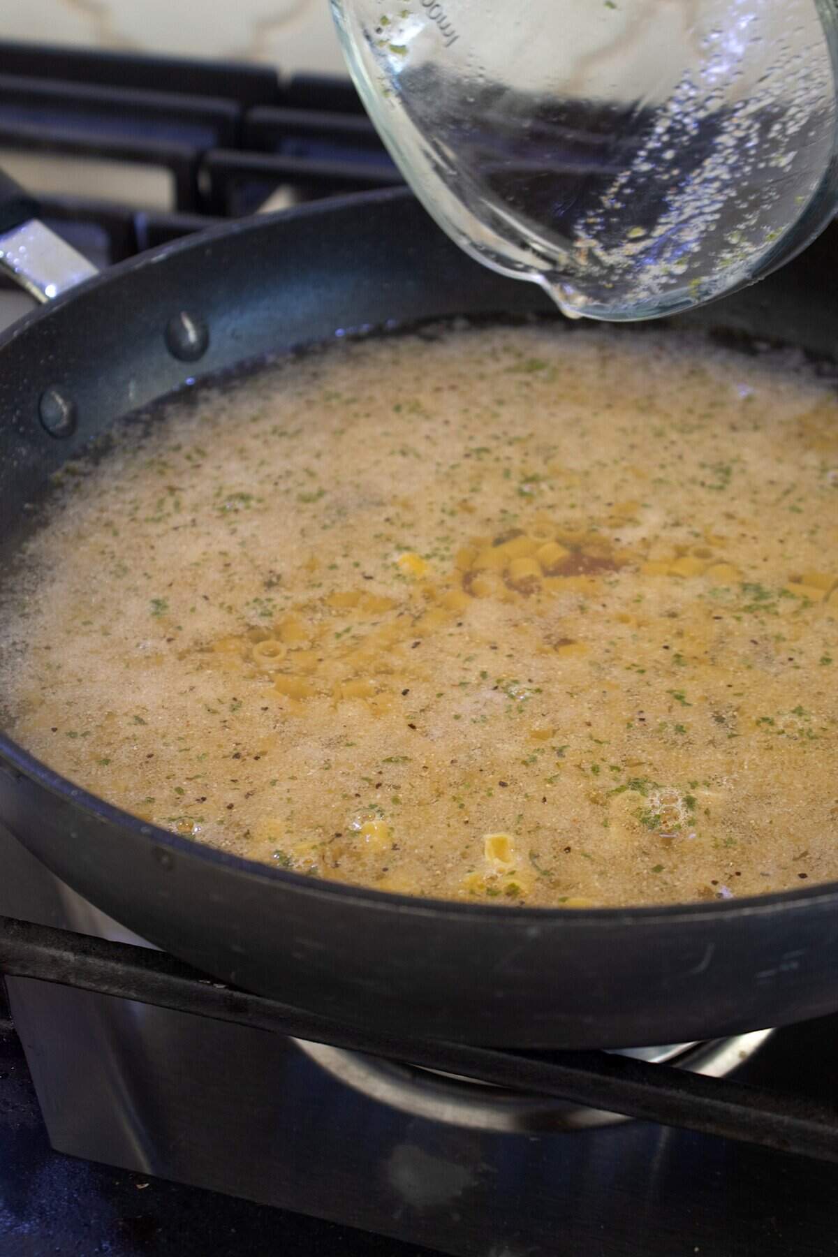 cooking ditalini pasta in a black skillet