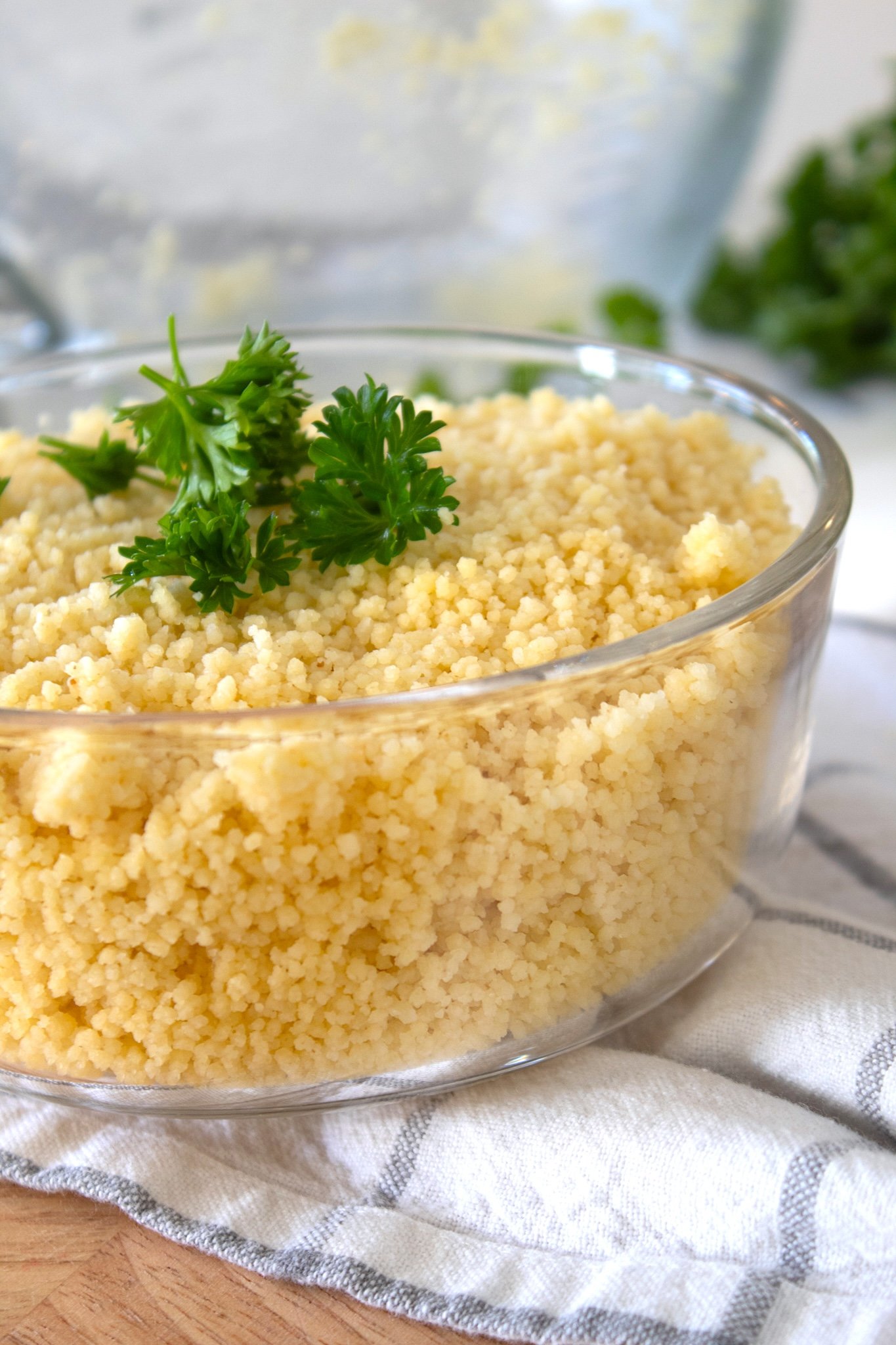 side view of couscous in a clear glass bowl with parsley garnish