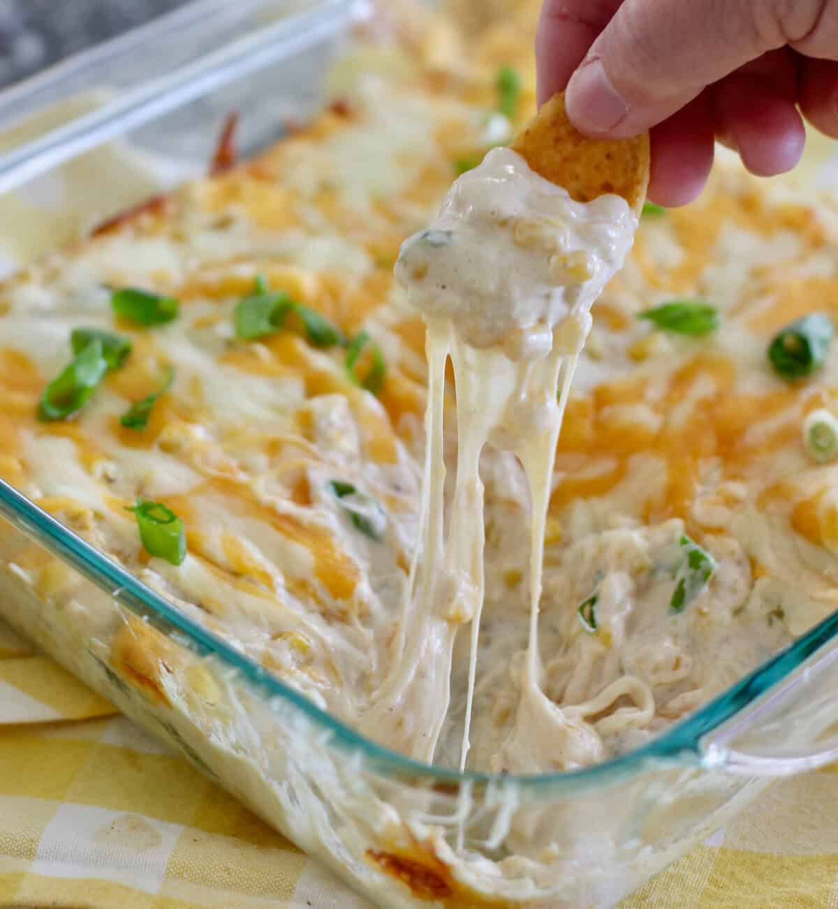 Hot corn dip out of the oven with frito scoop