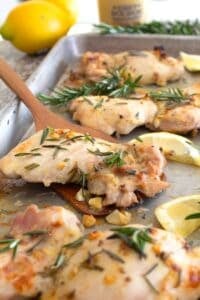 rosemary chicken on sheet pan with lemon garnish